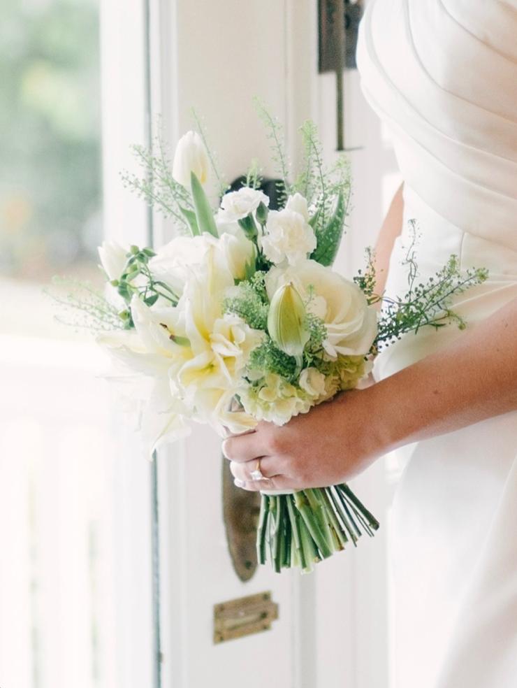A bride holding a cream and white bouquet of tulips, roses, and hydrangea, by Flowers by Syd