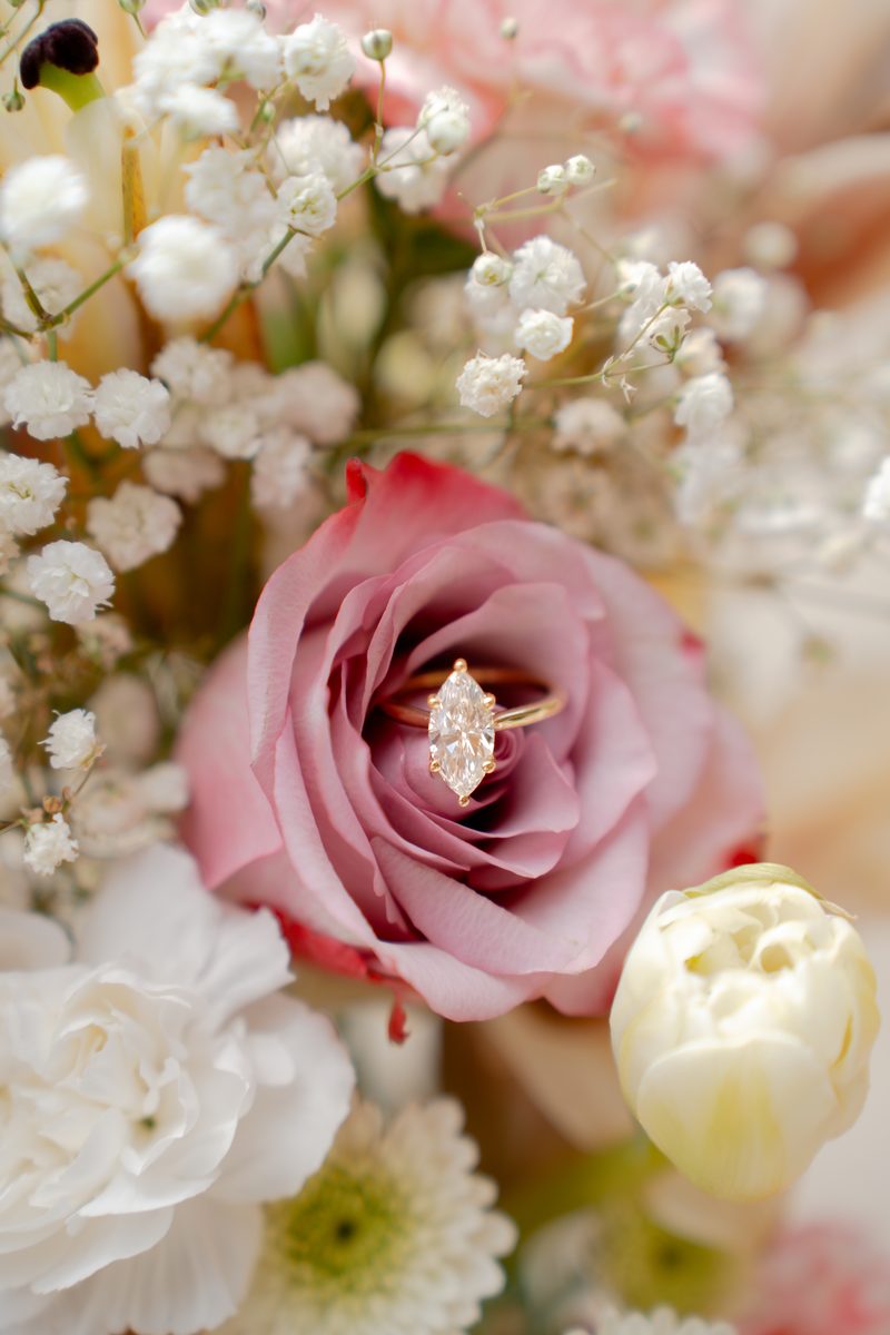 Engagement ring nestled in a mauve rose surrounded by baby's breath