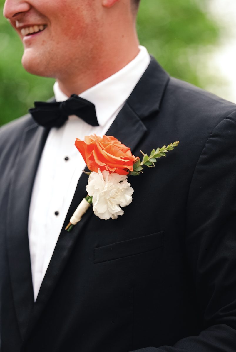 Groom's boutonniere with an orange rose and white carnation