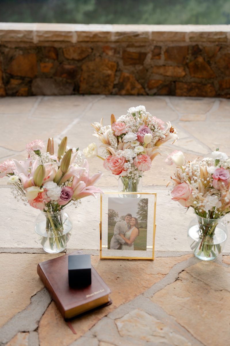 Vased florals beside a framed engagement photo and Bible