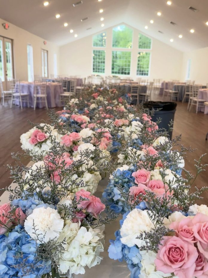 Long reception table lined with blush, blue, and white floral arrangements