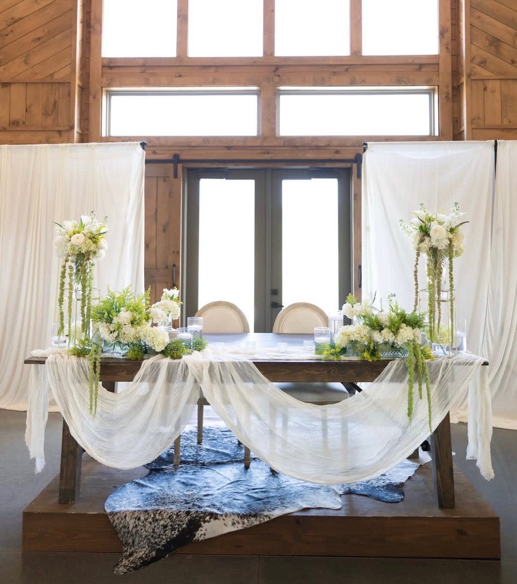 Barn wedding sweetheart table with tall white and green floral arrangements