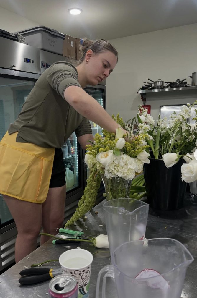 Sydnee hand-arranging a fresh white and green vased arrangement